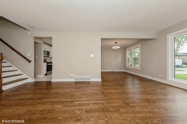 unfurnished living room featuring plenty of natural light and hardwood / wood-style floors