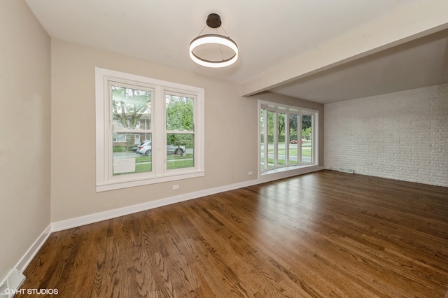 unfurnished room with wood-type flooring and brick wall