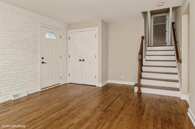 foyer with brick wall and dark hardwood / wood-style floors