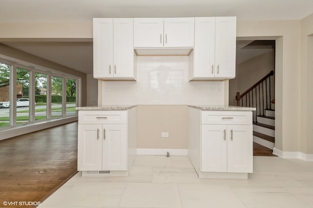 kitchen with light hardwood / wood-style flooring, decorative backsplash, and white cabinetry