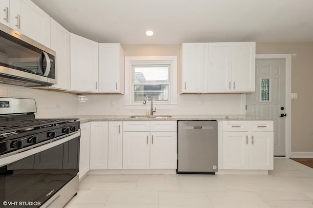 kitchen with appliances with stainless steel finishes, sink, decorative backsplash, light stone counters, and white cabinets