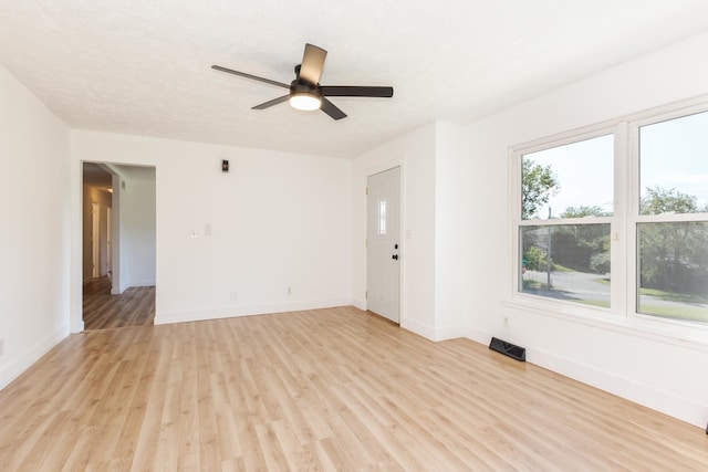 empty room with ceiling fan and light hardwood / wood-style floors