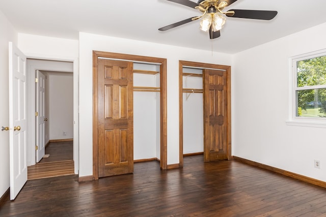 unfurnished bedroom with two closets, ceiling fan, and dark hardwood / wood-style flooring