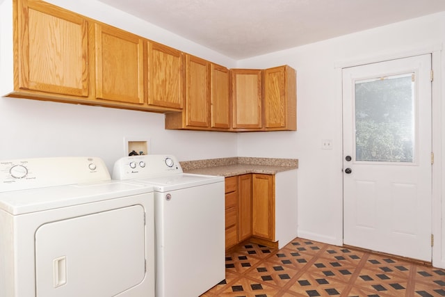 clothes washing area with cabinets and washing machine and clothes dryer