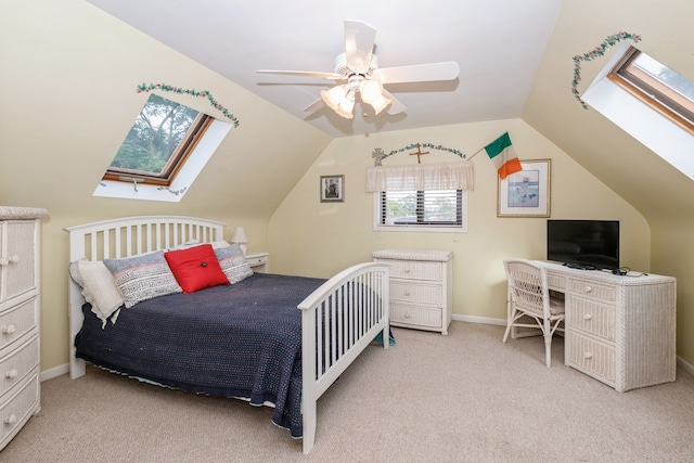 bedroom with ceiling fan, vaulted ceiling with skylight, and light colored carpet