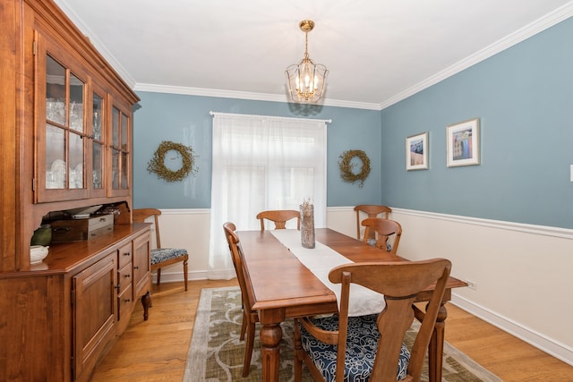 dining space featuring crown molding, an inviting chandelier, and light hardwood / wood-style floors