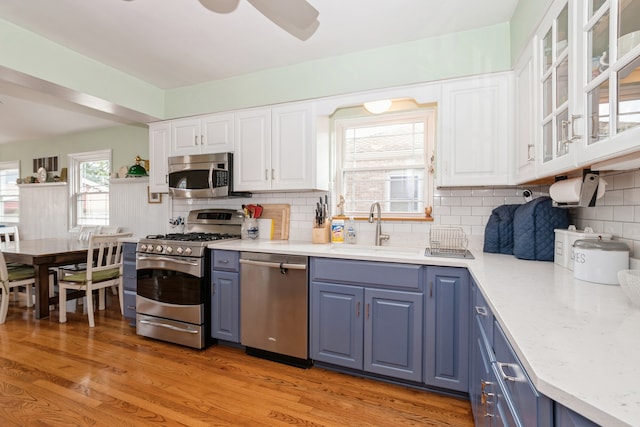 kitchen with light hardwood / wood-style flooring, stainless steel appliances, sink, decorative backsplash, and white cabinets