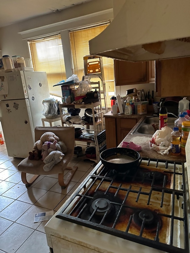 kitchen featuring light tile patterned floors, cooktop, sink, and range hood