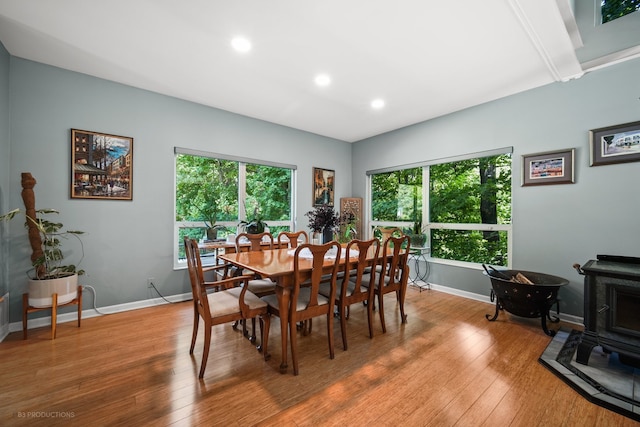 dining space with a wood stove, plenty of natural light, and wood-type flooring