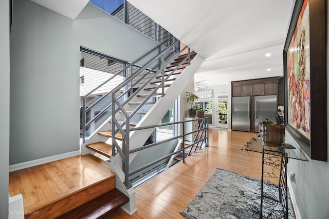 stairs with hardwood / wood-style floors and ceiling fan