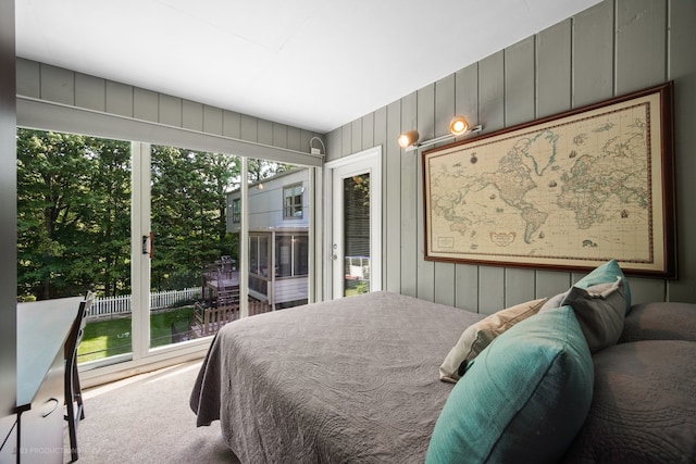 carpeted bedroom featuring wood walls and access to outside