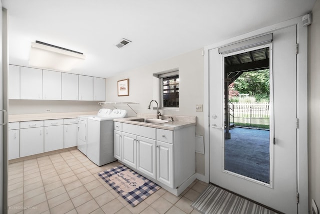 laundry area with light tile patterned floors, cabinets, washing machine and clothes dryer, and sink