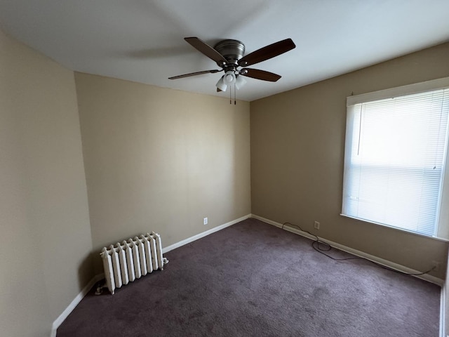 unfurnished room with a ceiling fan, radiator heating unit, baseboards, and dark colored carpet