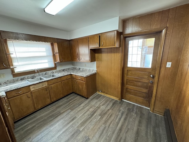 kitchen featuring light countertops, baseboard heating, brown cabinets, wood finished floors, and a sink