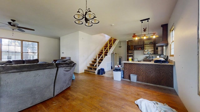 living room with ceiling fan with notable chandelier and hardwood / wood-style floors