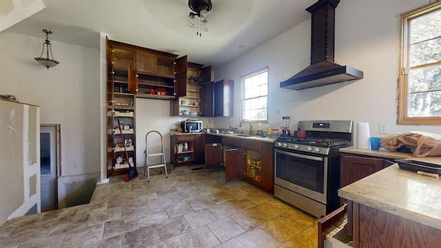 kitchen featuring decorative light fixtures, sink, island exhaust hood, ceiling fan, and stainless steel range with gas cooktop