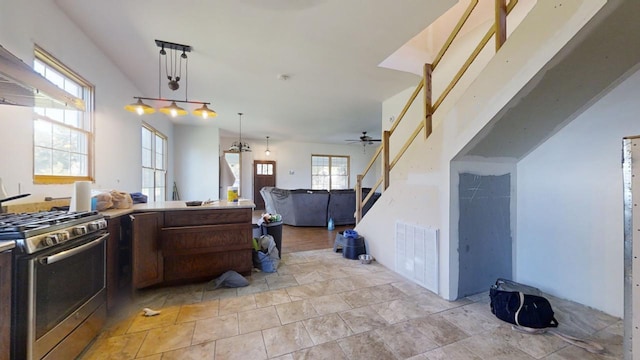 kitchen featuring ventilation hood, hanging light fixtures, gas stove, and ceiling fan