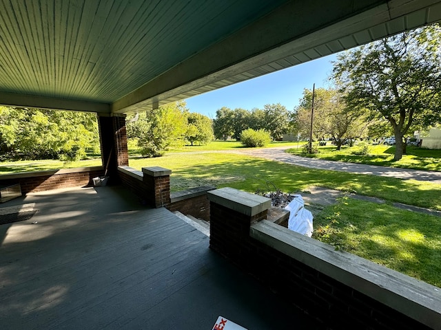 wooden terrace featuring a yard and a porch