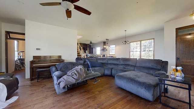 living room featuring dark wood-type flooring and ceiling fan with notable chandelier