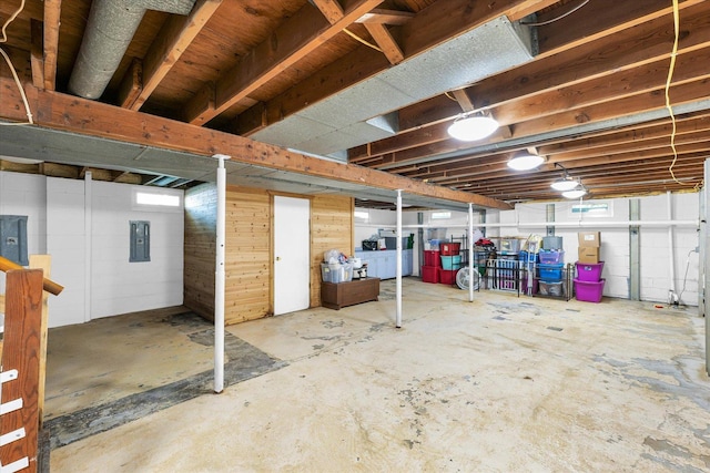 basement featuring wood walls and electric panel