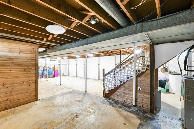 basement featuring gas water heater and wooden walls