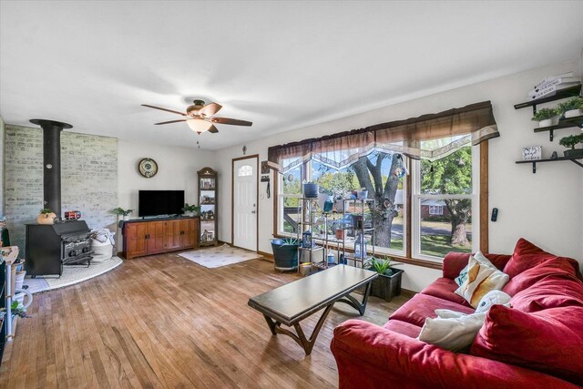 living room featuring hardwood / wood-style flooring, ceiling fan, and a wood stove