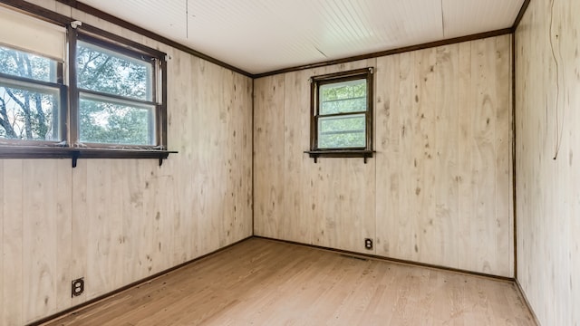 spare room with wood walls, light hardwood / wood-style floors, and ornamental molding