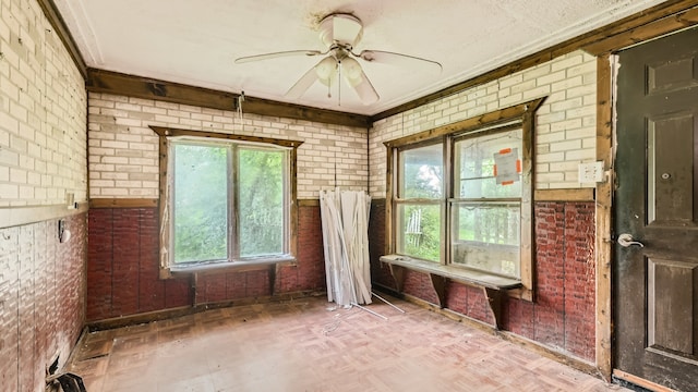 interior space featuring parquet floors, ceiling fan, ornamental molding, and brick wall