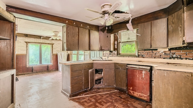 kitchen featuring parquet floors, dishwashing machine, sink, ceiling fan, and brick wall