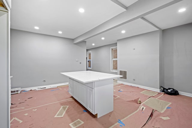 kitchen featuring a kitchen island, light stone counters, and white cabinets