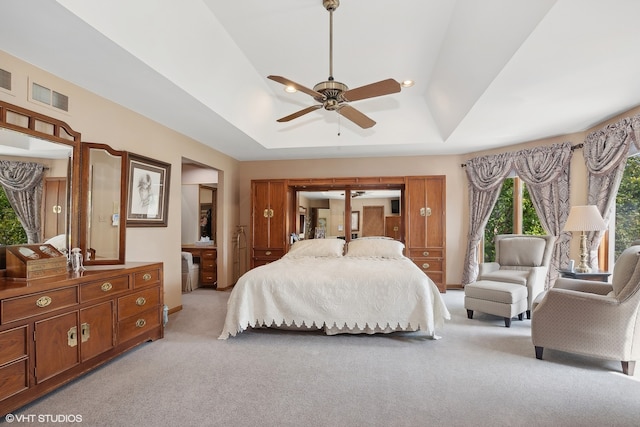 carpeted bedroom with ceiling fan and a tray ceiling