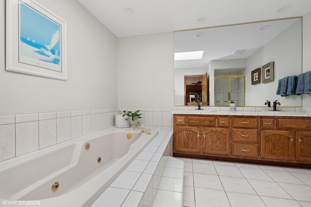 bathroom featuring tile patterned flooring, a skylight, separate shower and tub, and vanity