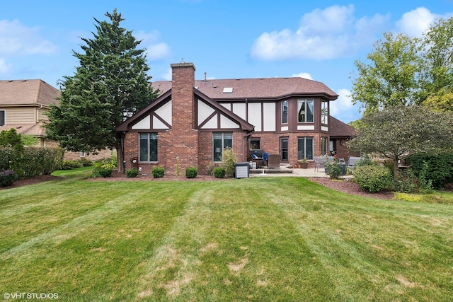 rear view of house featuring a lawn and a patio