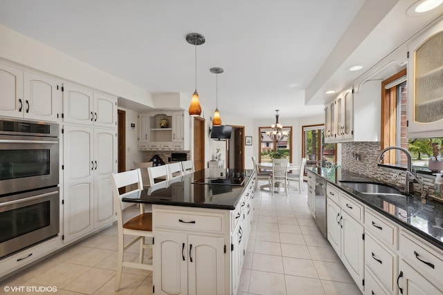 kitchen featuring white cabinets, a center island, decorative light fixtures, stainless steel appliances, and sink