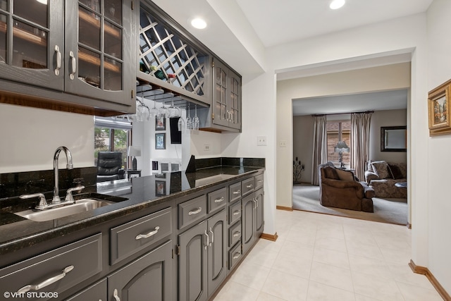 kitchen featuring dark stone countertops, light tile patterned flooring, and sink