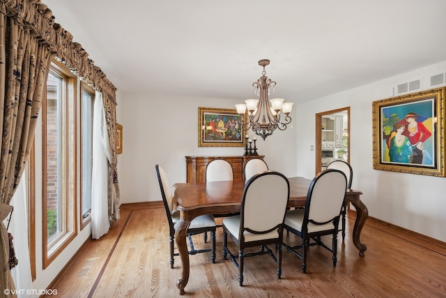 dining area featuring light wood-type flooring and an inviting chandelier