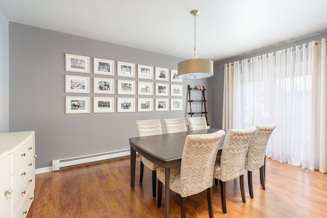 dining space featuring a baseboard heating unit and hardwood / wood-style flooring