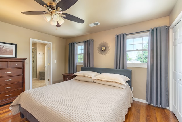 bedroom featuring ceiling fan, dark hardwood / wood-style floors, a closet, and multiple windows