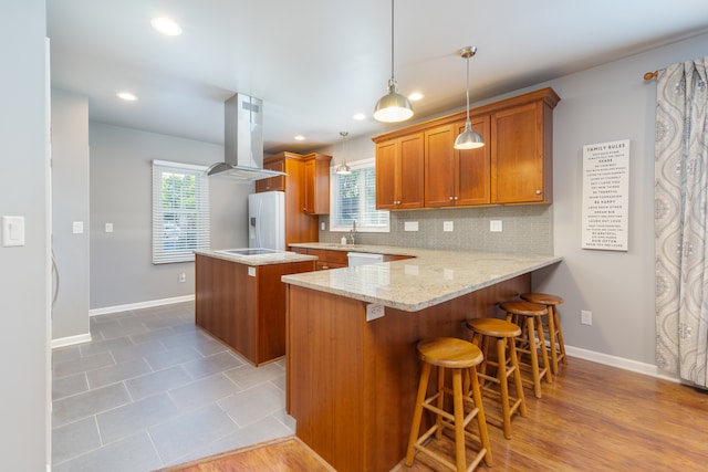 kitchen with a kitchen breakfast bar, decorative light fixtures, light hardwood / wood-style flooring, island range hood, and white fridge with ice dispenser