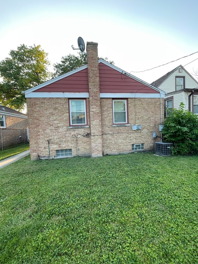 back of house featuring a lawn and central air condition unit