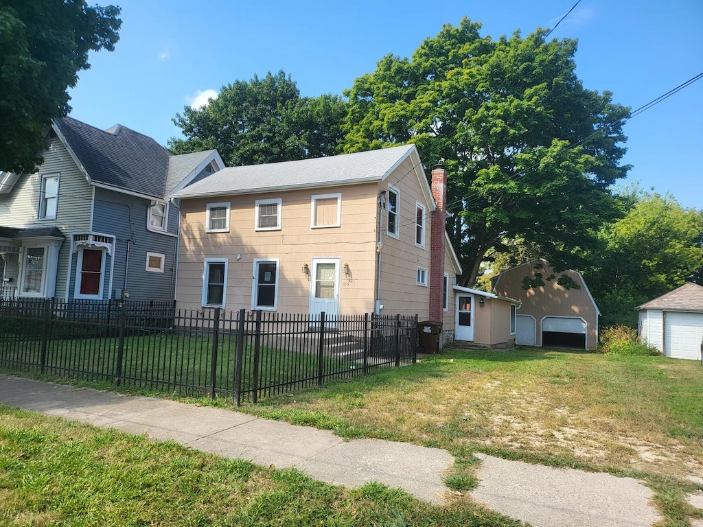 view of front of home with a garage, a front lawn, and an outbuilding