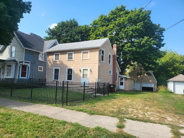 view of front of home with a garage, a front lawn, and an outbuilding