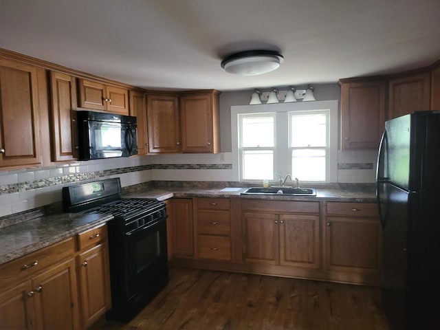 kitchen featuring dark stone counters, black appliances, sink, decorative backsplash, and dark hardwood / wood-style floors