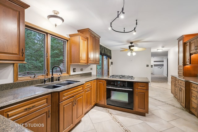 kitchen featuring light tile patterned floors, sink, ceiling fan, and black oven