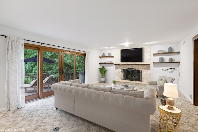 carpeted living room featuring a stone fireplace