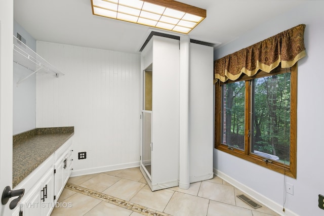 laundry room with wood walls and light tile patterned floors