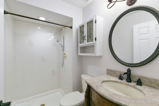 bathroom featuring vanity, toilet, and a tile shower