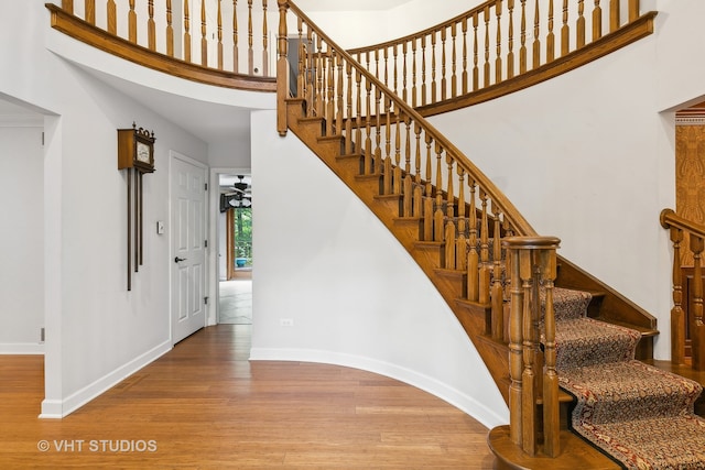 staircase with a high ceiling and wood-type flooring