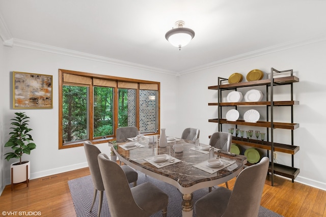 dining space featuring light wood-type flooring and crown molding