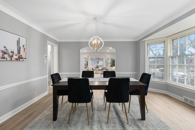 dining space with an inviting chandelier, crown molding, and wood-type flooring